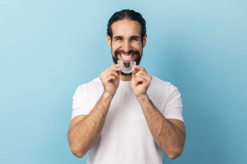 male standing holding his nightguard for bruxism
